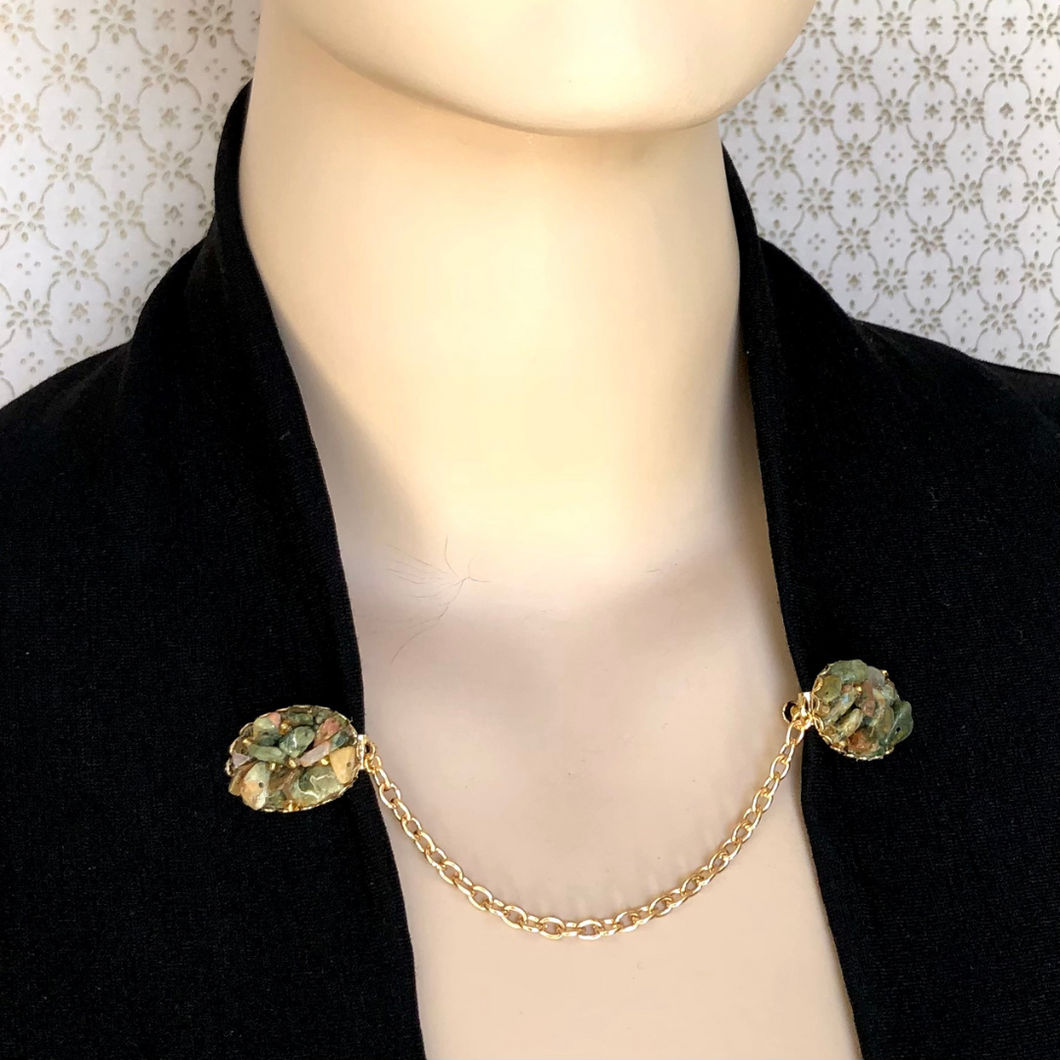 mannequin in black cardigan held closed by a sweater-guard or sweater clip set with chips of Ocean Jasper