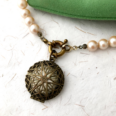 close-up of perfume locket and pearl beads 