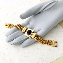 Load image into Gallery viewer, double strand gold chain bracelet with black glass cameo on mother-of-pearl on a grey gloved hand
