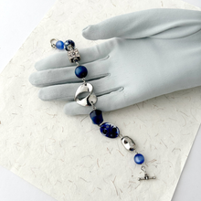 Load image into Gallery viewer, bracelet made with vintage and repurposed beads in blue and silver displayed on a grey gloved hand
