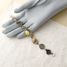 Load image into Gallery viewer, Decorative bracelet with yellow stones and silver accents displayed on a hand wearing a gray glove.
