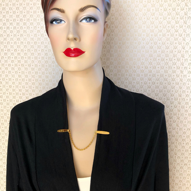 mannequin modelling a gold plated sweater clip on a black jacket