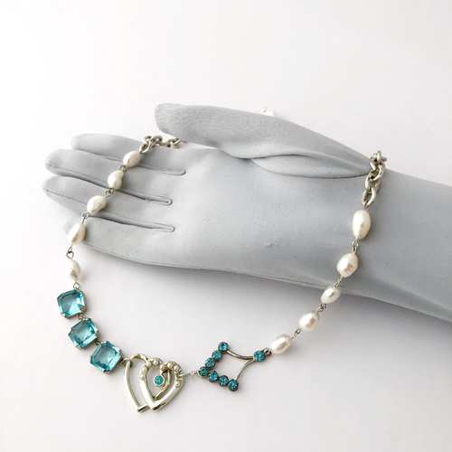 necklace made with vintage aqua rhinestone necklace, brooch and earring fragments and freshwater pearls displayed on a gloved hand