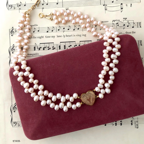necklace of pink freshwater pearls and vintage sweetheart focal on a vintage jewellery box  