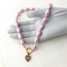 Load image into Gallery viewer, necklace of vintage rice-shaped pearlised beads in soft amethyst pink with vintage amethyst heart pendant displayed on a gloved hand
