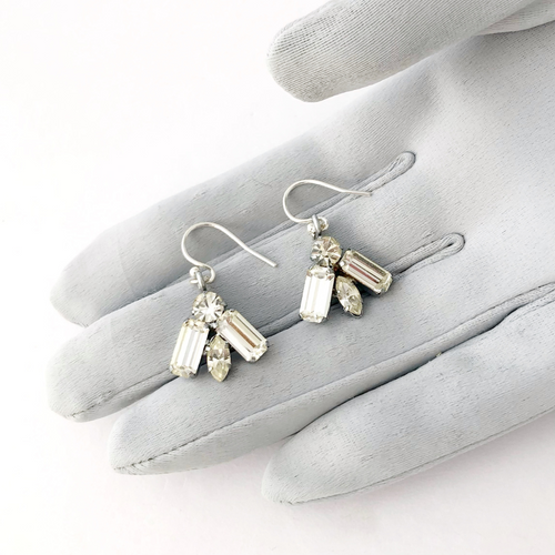 a pair of rhinestone earrings on a gloved hand