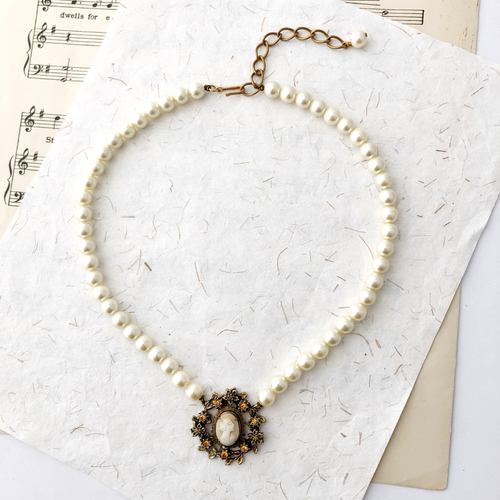 Pearl necklace with cameo focal on a textured paper background