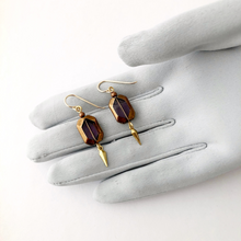 Load image into Gallery viewer, vintage amethyst glass stone earrings with gold edges and a brass dangle displayed on a gloved hand
