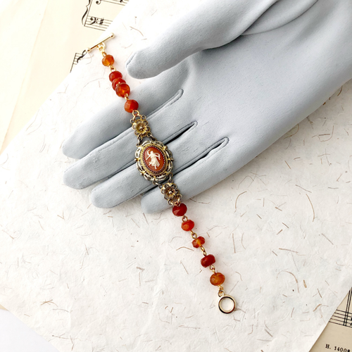 Bracelet with vintage cameo and Carnelian beads displayed on a gloved hand
