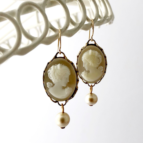 vintage cameo earrings with pearl accents hanging against a white background