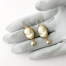 Load image into Gallery viewer, vintage cameo earrings with pearl accents displayed on a grey gloved hand

