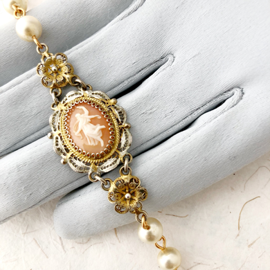 Close-up of bracelet with vintage cameo and pearl beads on a gloved hand
