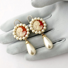 Load image into Gallery viewer, Pair of earrings with vintage cameos and pearls on a grey gloved hand

