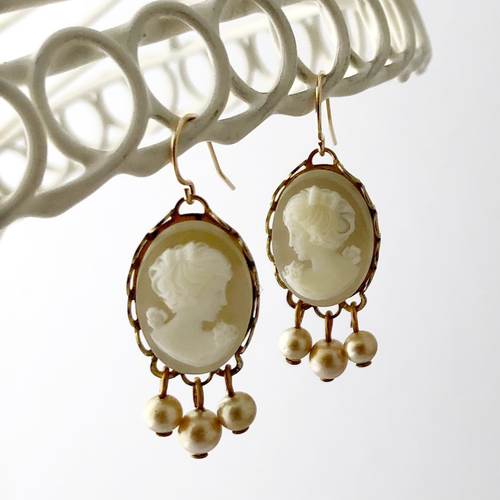 Vintage cameo earrings with pearl accents on a white background