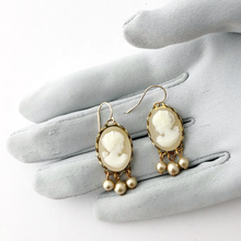 Load image into Gallery viewer, Vintage cameo earrings with pearl accents displayed on a gloved hand
