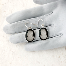 Load image into Gallery viewer, Cameo earrings displayed on a grey gloved hand on a pale background
