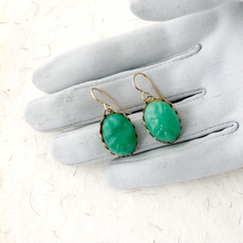 Load image into Gallery viewer, Vintage Peking glass oval stones in brass plated steel settings displayed on a grey gloved hand
