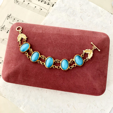 Load image into Gallery viewer, bracelet with large blue glass stones and gold links displayed on a red velvet jewellery box
