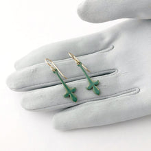 Load image into Gallery viewer, green fleur-de-lys drop earrings displayed on a gloved hand
