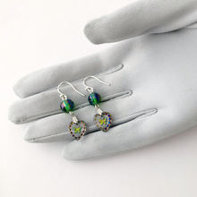 Load image into Gallery viewer, earrings made with glass intaglio stones incised with iridescent butterflies displayed on a gloved hand
