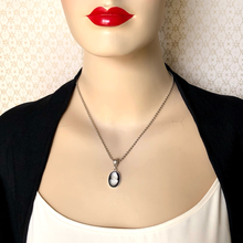 Load image into Gallery viewer, Mannequin wearing a necklace with an oval cameo pendant against a patterned wall.
