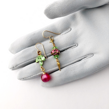 Load image into Gallery viewer, asymmetric earrings in pink and green on a gloved hand
