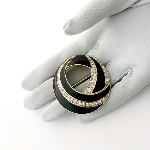 vintage brooch in black enamel with rhinestones displayed on a gloved hand